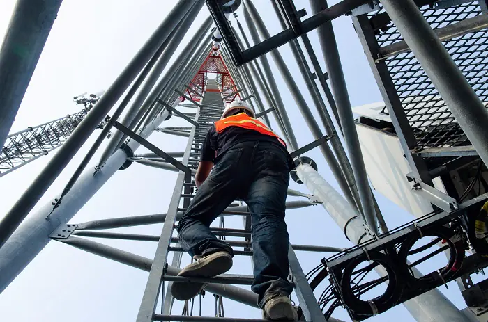 Worker climbs metal communication tower